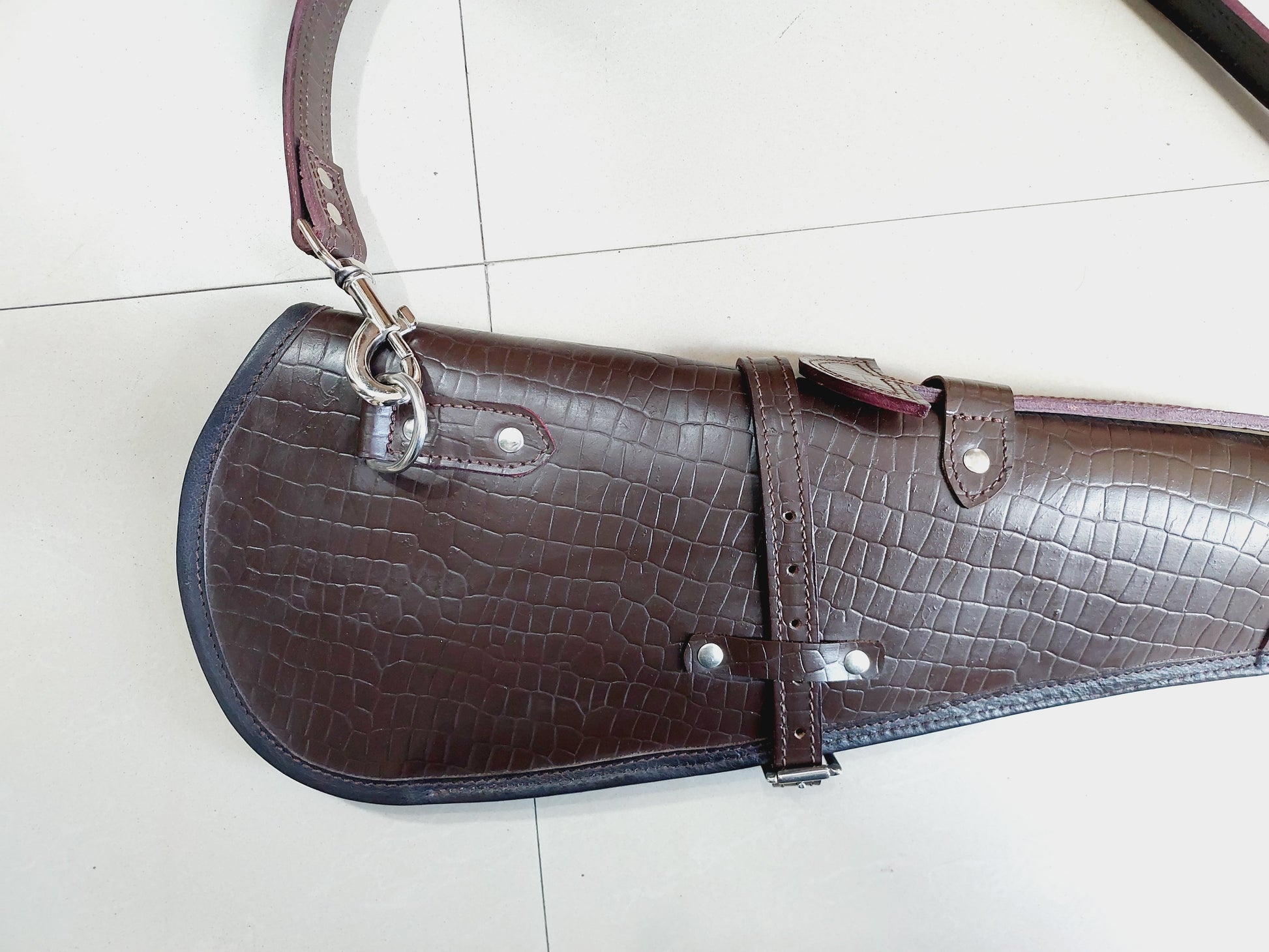 33 inch croc embossed leather rifle scabbard with adjustable strap

Rifle case mounted on wooden wall – western leather design

Inside view of fleece-lined gun scabbard

Full-length view of rifle scabbard with stainless hardware

Leather scabbard displayed on floor – cowboy style

Zoom-in of croc leather pattern with hook and buckle

Hand-holding leather rifle scabbard – easy grip

Informative banner for croc leather scabbard – genuine leather, stainless hardware

Rifle inside scabbard – ammo loop visible